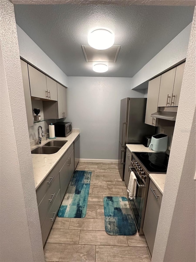 4800 S Semoran Blvd Unit 101, Orlando, FL 32822 - kitchen featuring a sink, stainless steel appliances, under cabinet range hood, gray cabinetry, and wood finish floors