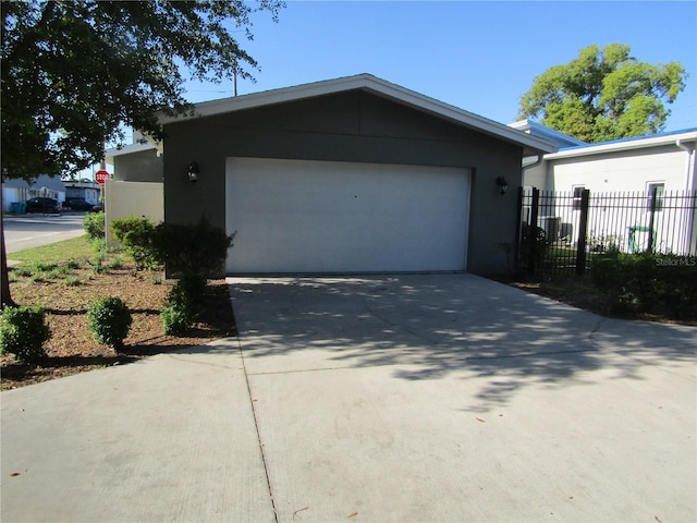 view of property exterior with fence, driveway, a garage, and stucco siding