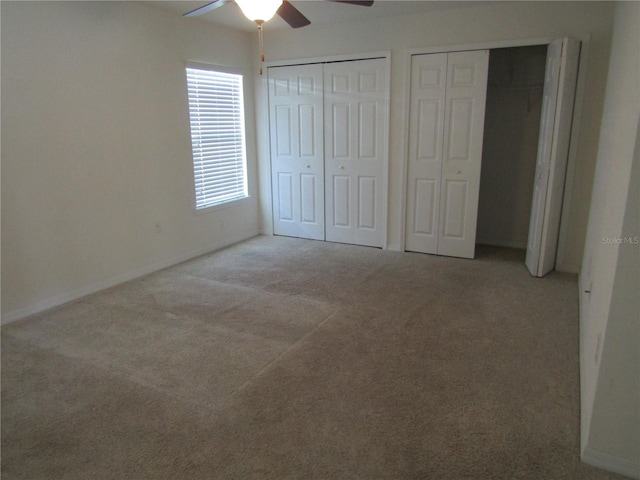 unfurnished bedroom featuring two closets, ceiling fan, baseboards, and carpet