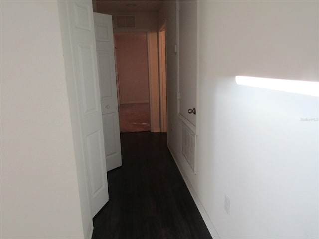hall featuring dark wood-type flooring and visible vents