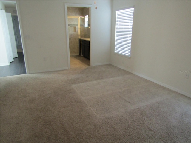 spare room featuring light colored carpet and baseboards
