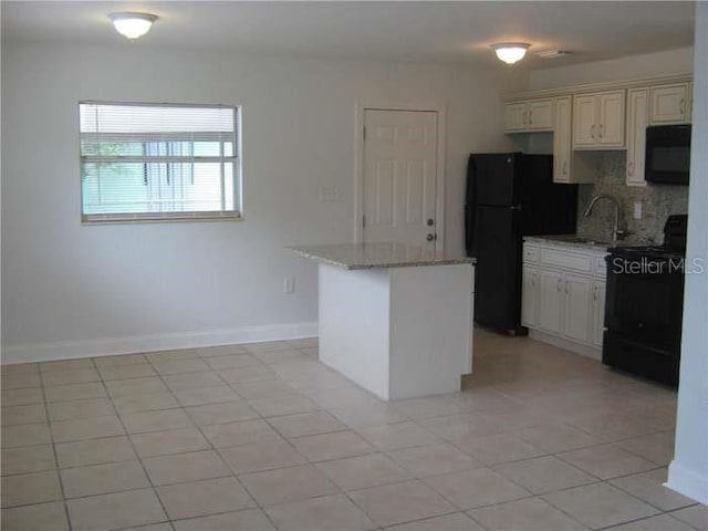kitchen featuring a center island, black appliances, backsplash, light tile patterned flooring, and light stone counters