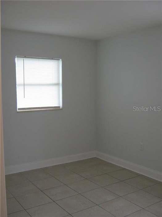spare room with light tile patterned floors and baseboards