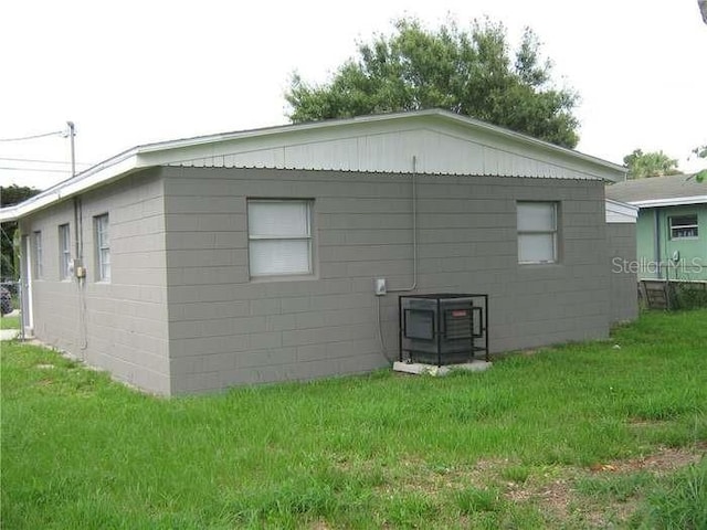 view of property exterior with concrete block siding and a lawn