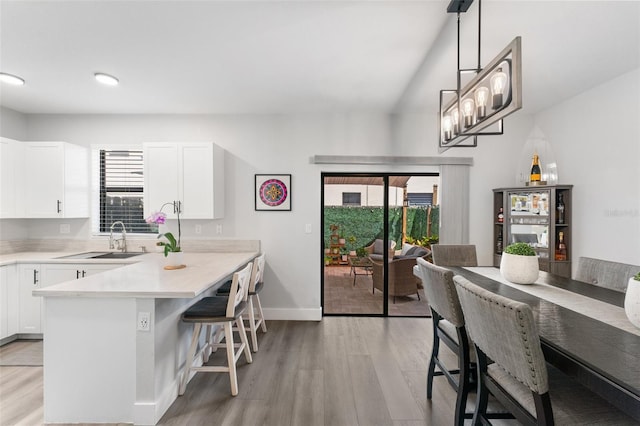 549 NE 206th Ln, Miami, FL 33179 - kitchen with a breakfast bar, light wood-type flooring, white cabinetry, and a sink