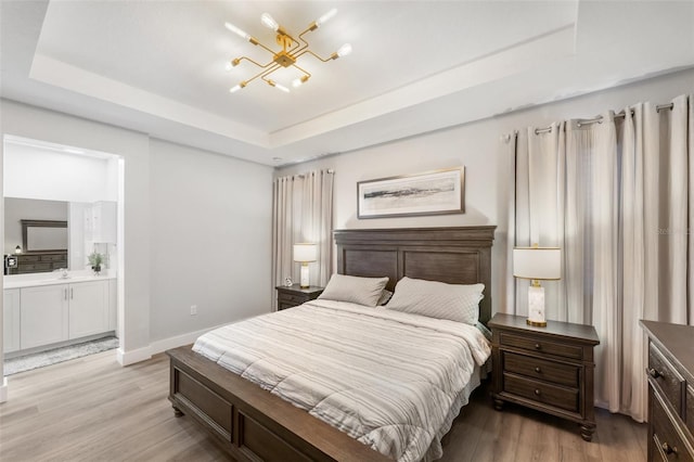 549 NE 206th Ln, Miami, FL 33179 - bedroom featuring ensuite bathroom, a chandelier, light wood-style floors, a tray ceiling, and baseboards