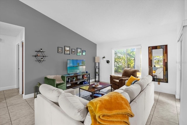 living area featuring light tile patterned floors, baseboards, and vaulted ceiling