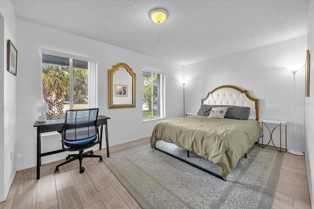 bedroom featuring a textured ceiling, wood finished floors, and multiple windows