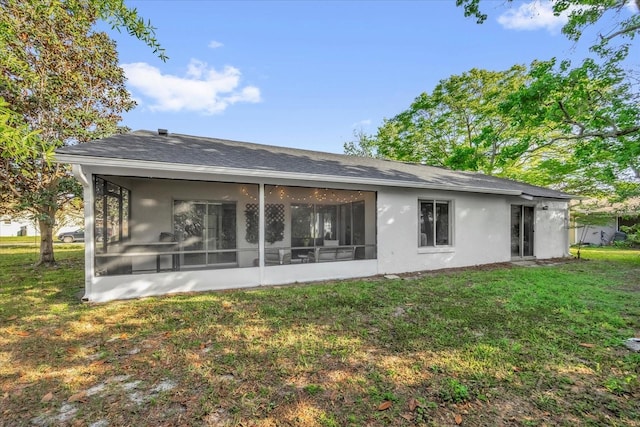 rear view of house featuring a sunroom, a lawn, and stucco siding
