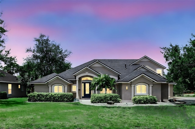 ranch-style house featuring stucco siding and a lawn