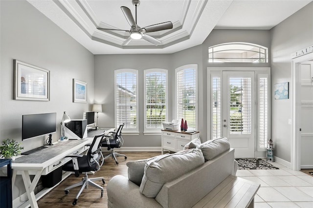 office space featuring ceiling fan, ornamental molding, a raised ceiling, and baseboards