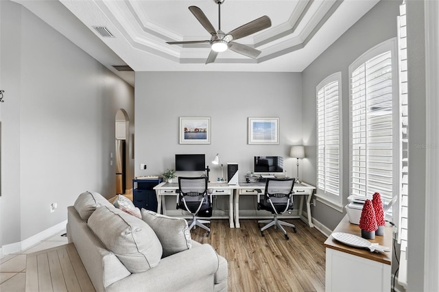 office featuring plenty of natural light, a tray ceiling, a ceiling fan, light wood-style floors, and crown molding