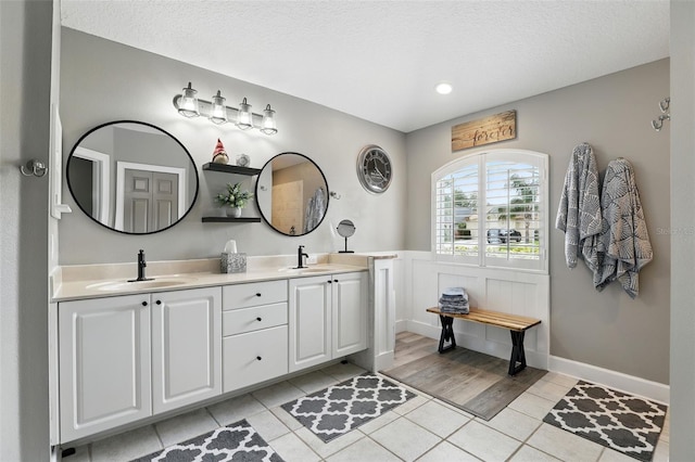 bathroom with tile patterned floors, double vanity, and a textured ceiling
