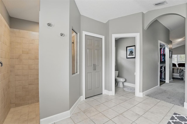 bathroom with a closet, walk in shower, tile patterned flooring, and toilet