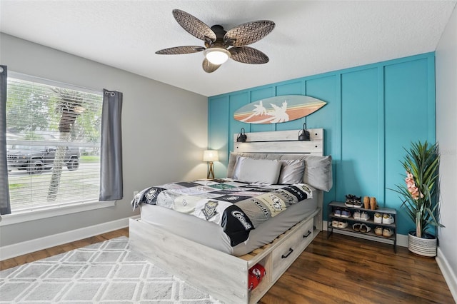 bedroom featuring dark wood-type flooring, baseboards, ceiling fan, and a textured ceiling