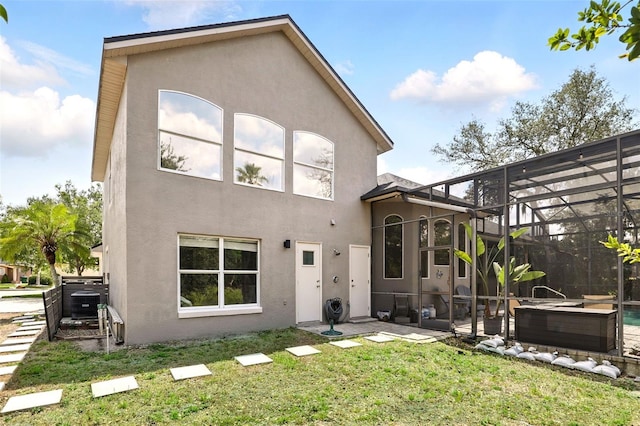 rear view of house featuring stucco siding, a yard, glass enclosure, and central AC unit