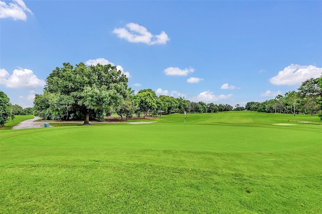 view of property's community featuring view of scattered trees, view of golf course, and an area to practice putting