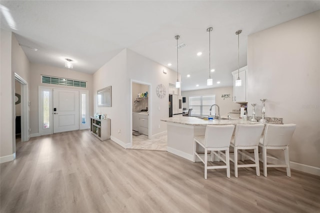 8137 Merano Ave, Fort Pierce, FL 34951 - kitchen with white cabinets, a peninsula, light wood-style floors, and baseboards