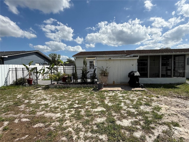 back of property featuring a sunroom and fence