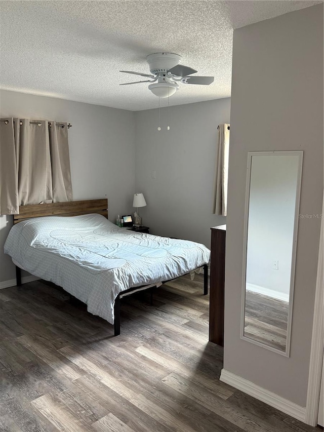 bedroom with ceiling fan, a textured ceiling, baseboards, and wood finished floors