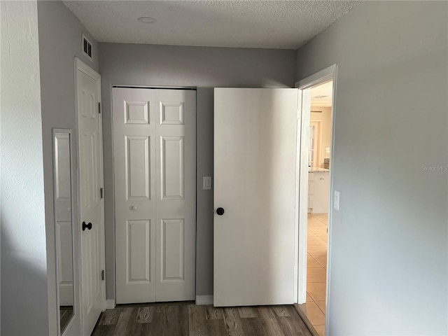 interior space featuring a textured ceiling, wood finished floors, and visible vents