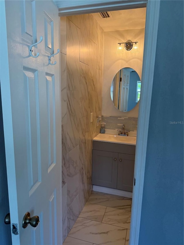 bathroom featuring vanity, marble finish floor, visible vents, and decorative backsplash