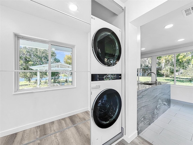 407 Sheryl Dr, Deltona, FL 32738 - washroom featuring a sink, visible vents, stacked washer / dryer, wood finished floors, and laundry area