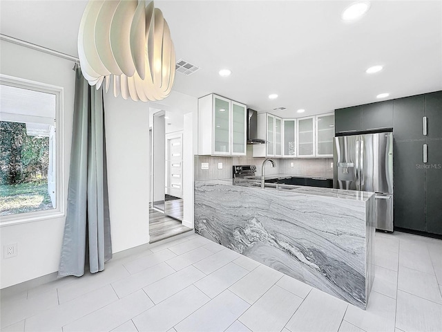 407 Sheryl Dr, Deltona, FL 32738 - kitchen with light stone counters, backsplash, visible vents, wall chimney exhaust hood, and stainless steel refrigerator with ice dispenser