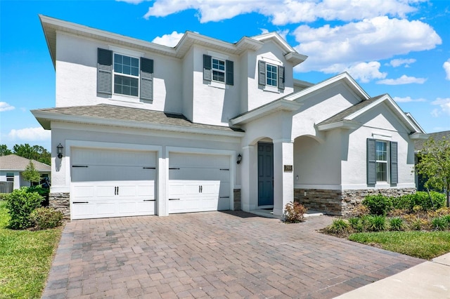 traditional-style home featuring a garage, stucco siding, and stone siding