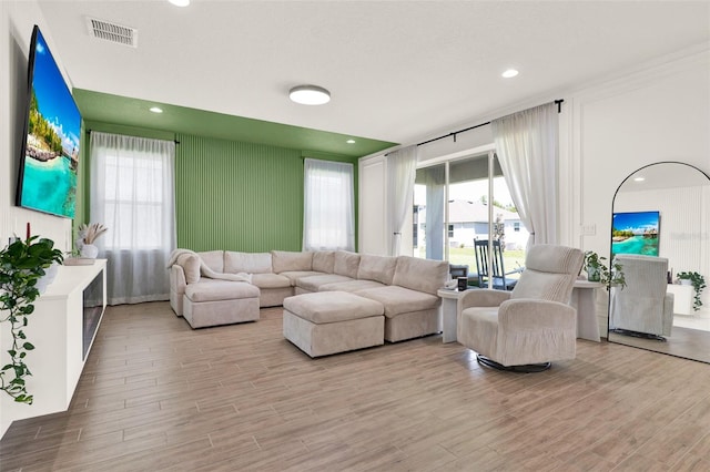 living room featuring light wood-style flooring, visible vents, and a wealth of natural light
