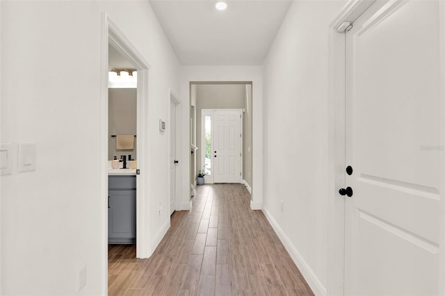 hall with light wood-style flooring and baseboards