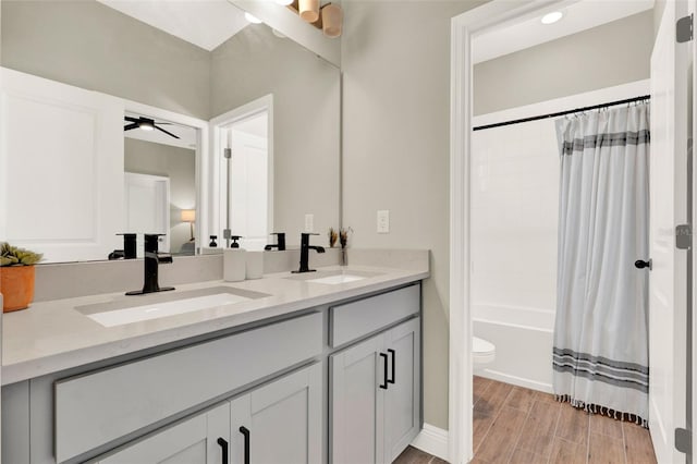 full bath featuring ceiling fan, wood finished floors, double vanity, and a sink