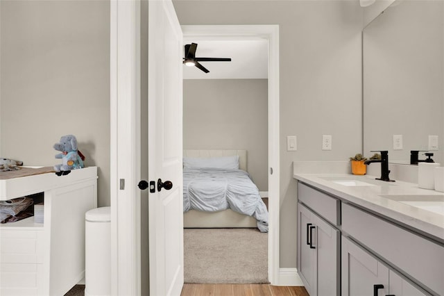bathroom featuring double vanity, ensuite bath, a ceiling fan, a sink, and wood finished floors
