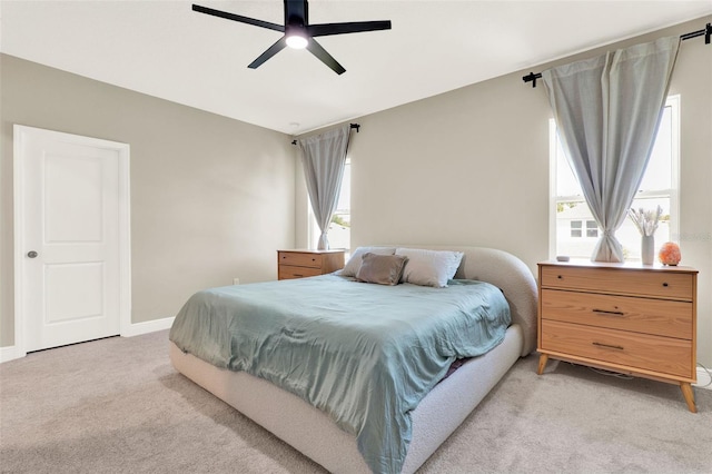 bedroom with ceiling fan, light carpet, and baseboards