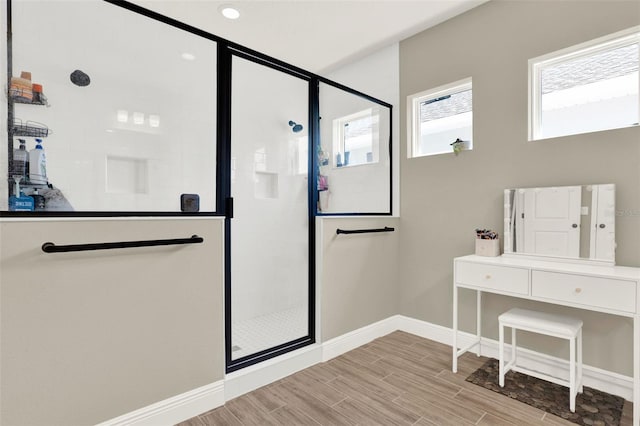 bathroom with baseboards, a shower stall, and wood finished floors