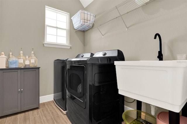laundry area with light wood-type flooring, washing machine and clothes dryer, and baseboards
