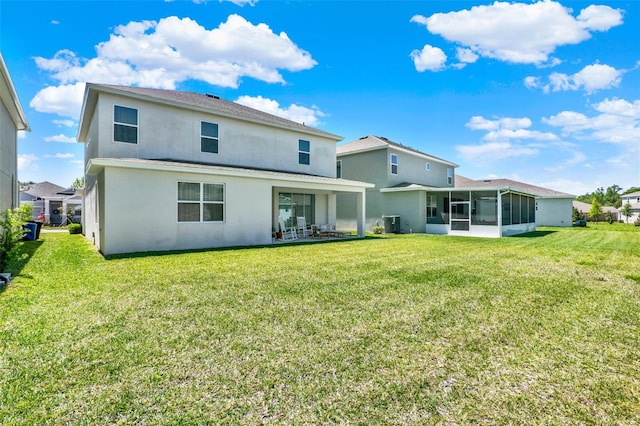 back of property with a sunroom, stucco siding, and a lawn
