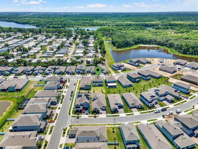 drone / aerial view with a wooded view, a residential view, and a water view