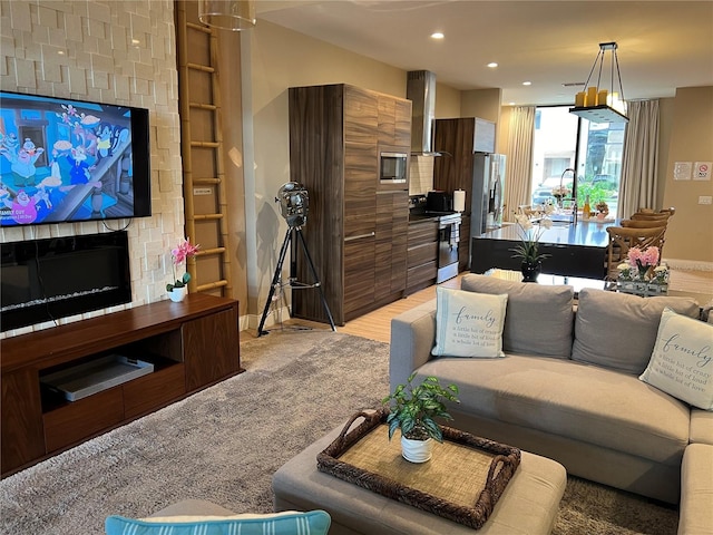 living area with a large fireplace, baseboards, recessed lighting, and light colored carpet