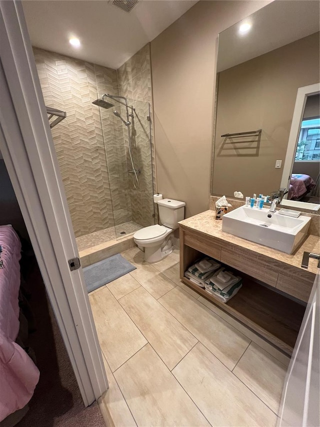 bathroom featuring tile patterned flooring, vanity, toilet, recessed lighting, and tiled shower