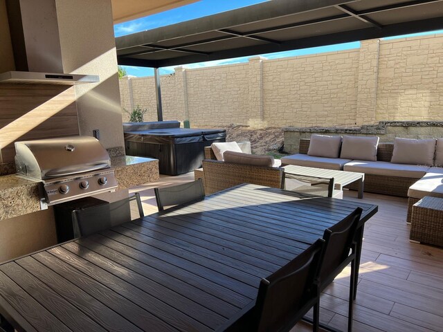 wooden deck featuring a hot tub, an outdoor hangout area, a fenced backyard, and a grill