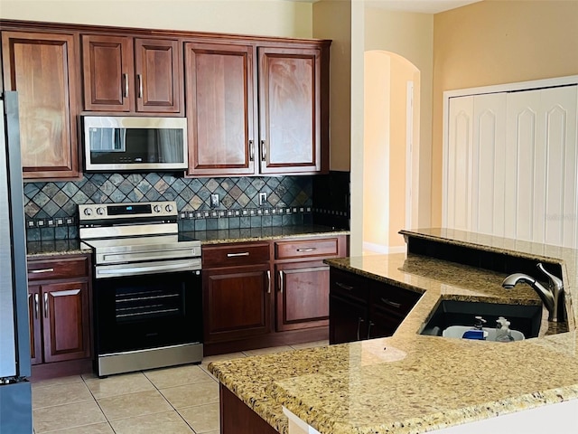 702 Palenci Ct, Winter Springs, FL 32708 - kitchen featuring light tile patterned floors, backsplash, stainless steel appliances, arched walkways, and a sink