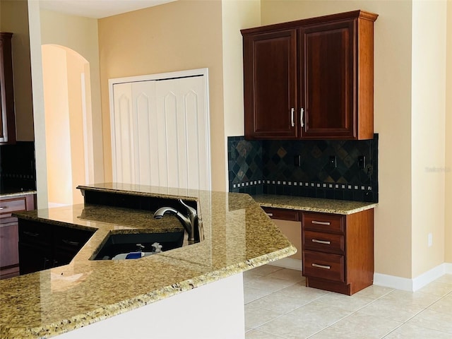 702 Palenci Ct, Winter Springs, FL 32708 - kitchen with arched walkways, a sink, light stone countertops, decorative backsplash, and light tile patterned flooring