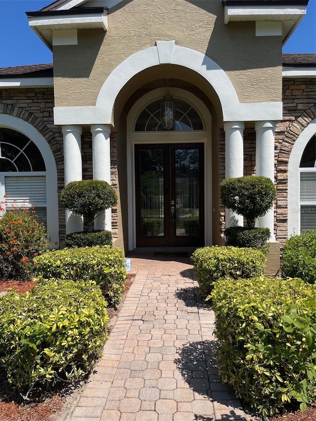 702 Palenci Ct, Winter Springs, FL 32708 - view of exterior entry featuring french doors, stone siding, and stucco siding