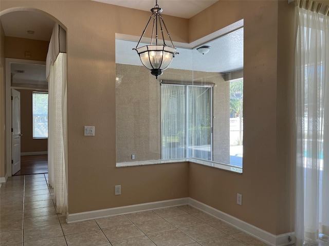 702 Palenci Ct, Winter Springs, FL 32708 - unfurnished dining area with arched walkways, baseboards, tile patterned flooring, and an inviting chandelier