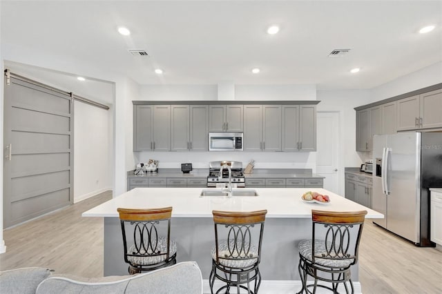 15865 Key Biscayne Ln, Loxahatchee, FL 33470 - kitchen with appliances with stainless steel finishes, gray cabinetry, a kitchen breakfast bar, light wood finished floors, and recessed lighting