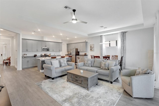 15865 Key Biscayne Ln, Loxahatchee, FL 33470 - living room with a raised ceiling, recessed lighting, light wood-style floors, ceiling fan, and baseboards