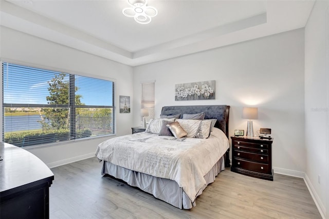 15865 Key Biscayne Ln, Loxahatchee, FL 33470 - bedroom featuring a raised ceiling, light wood-style floors, and baseboards