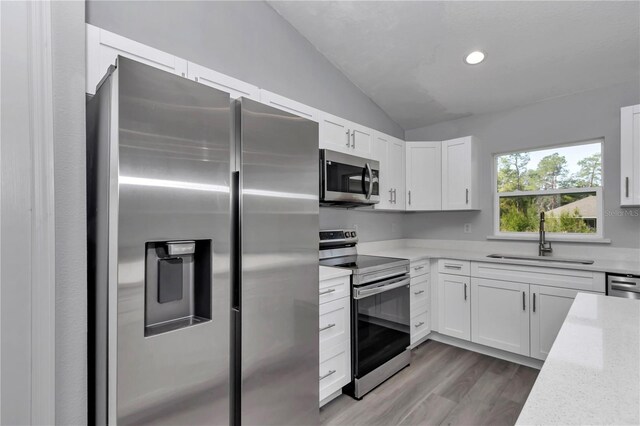17468 SW 36th Ter, Ocala, FL 34473 - kitchen with a sink, white cabinets, vaulted ceiling, and stainless steel appliances