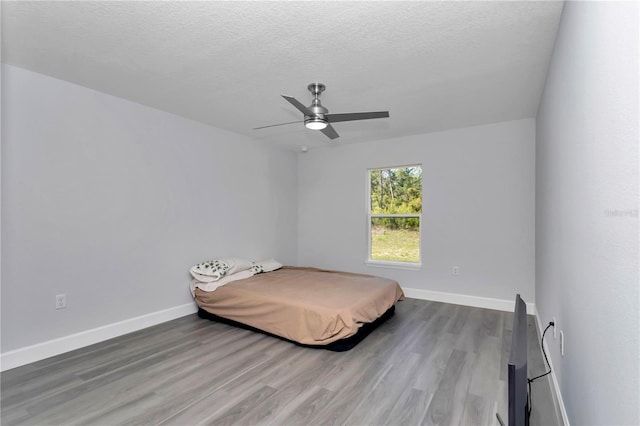 17468 SW 36th Ter, Ocala, FL 34473 - bedroom featuring baseboards, a textured ceiling, a ceiling fan, and wood finished floors